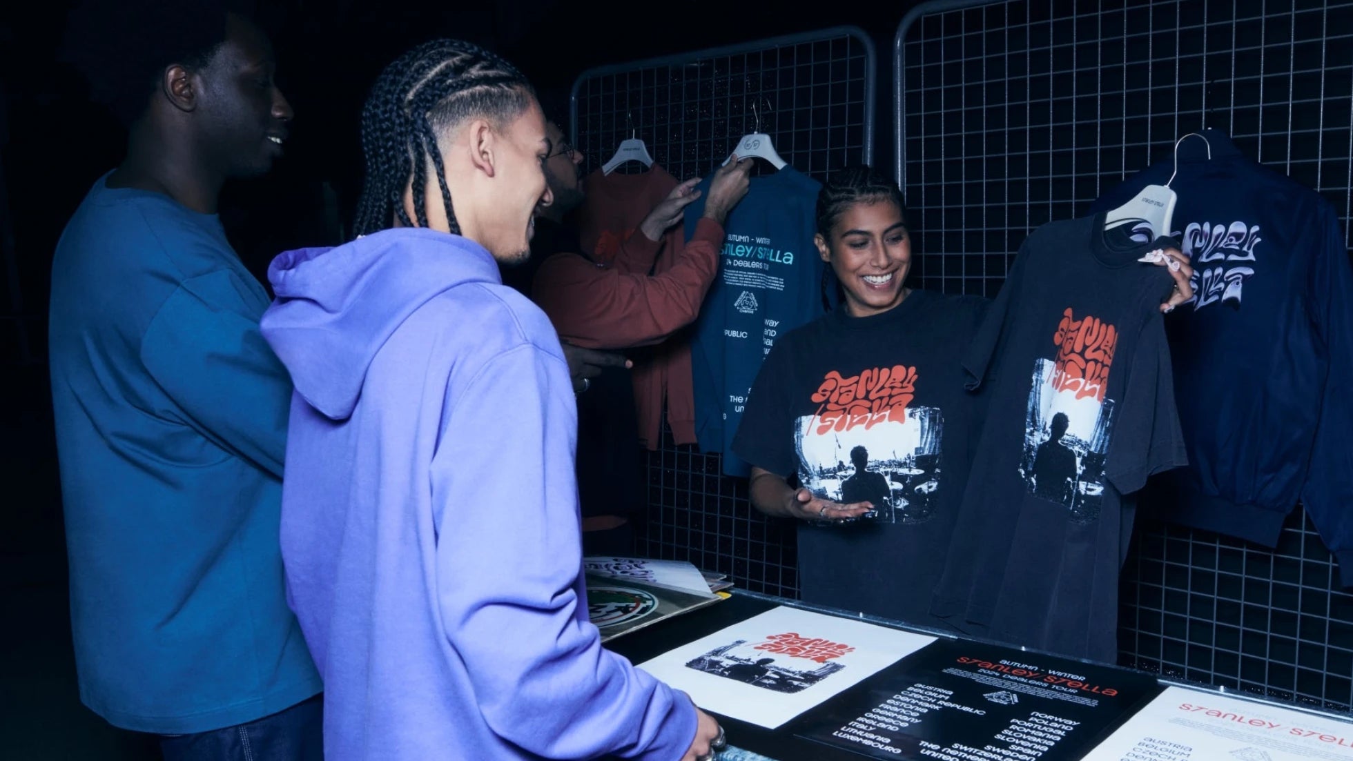People interacting with merchandise at a display stand in a dark setting
